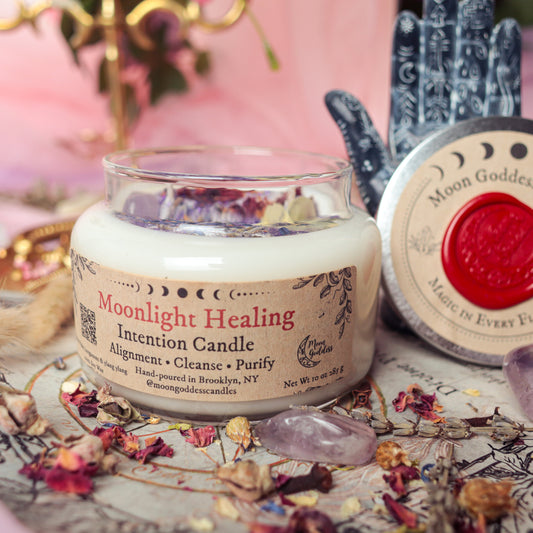 Moonlight Healing Intention Candle by Moon Goddess Candles, hand-poured in Brooklyn and infused with ylang ylang and dried florals, surrounded by amethyst crystals and botanical elements to promote alignment, cleansing, and energetic purification.